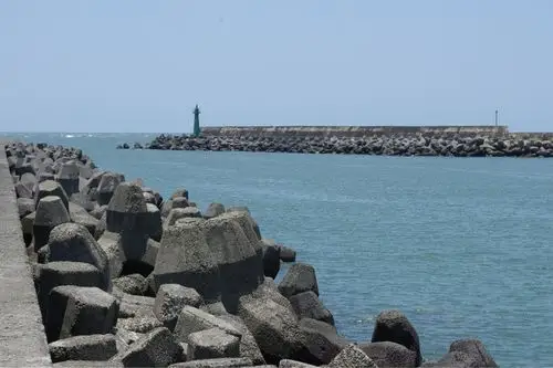 码头上不见渔人的踪影,只有一群群破浪石伫立在岸边.